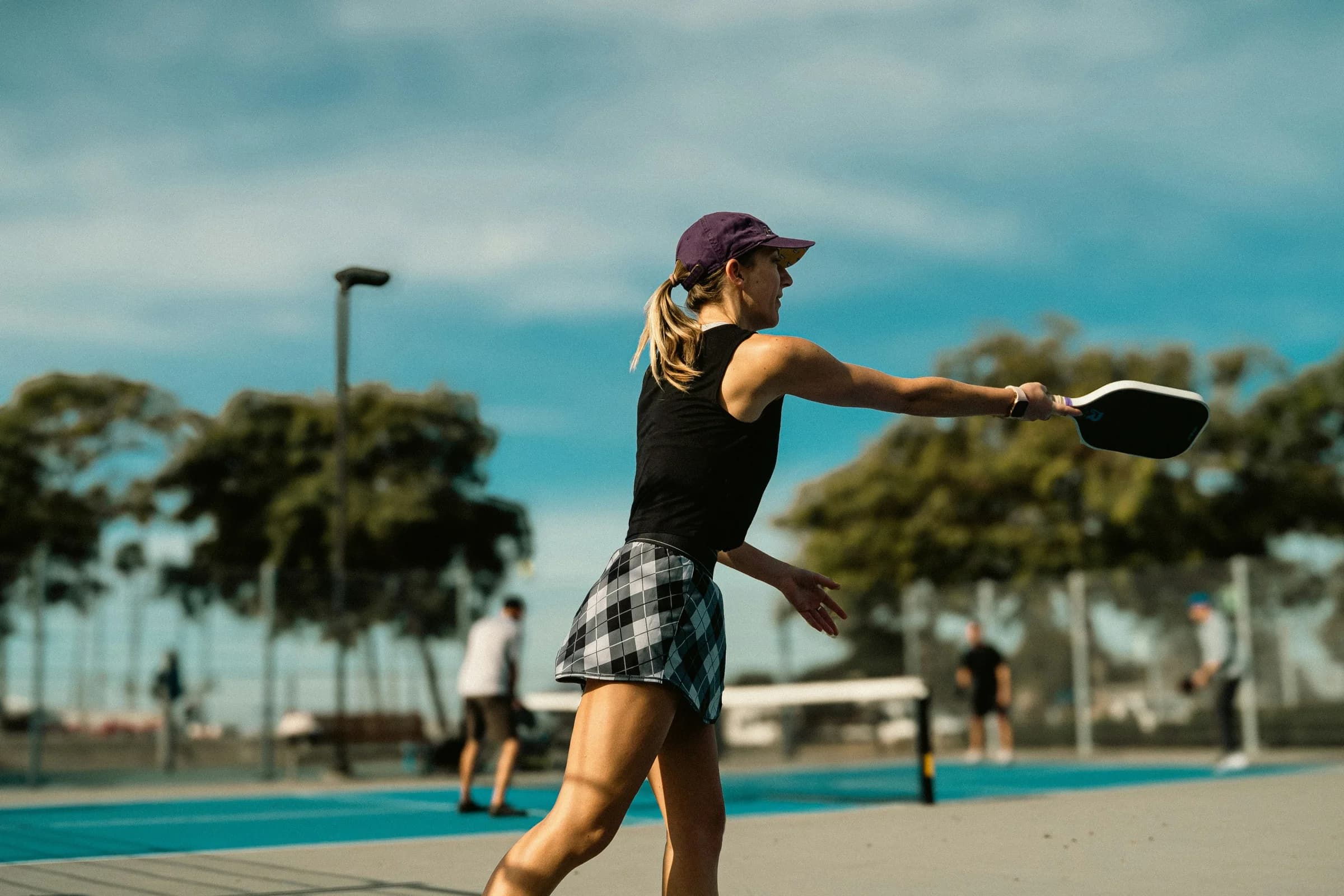 A pickleball player following through on an outdoor court